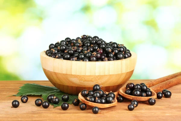 Frische schwarze Johannisbeere in Holzschale auf grünem Hintergrund Nahaufnahme — Stockfoto