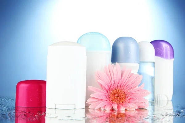 Deodorant botttles met bloem op blauwe achtergrond — Stockfoto