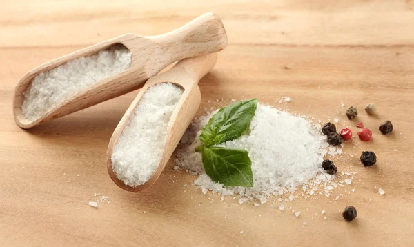 Соль со свежим базиликом и перцем на деревянном столе — стоковое фото