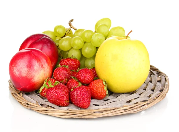 Спелые сладкие фрукты и ягоды на плетеном коврике изолированы на белом — стоковое фото