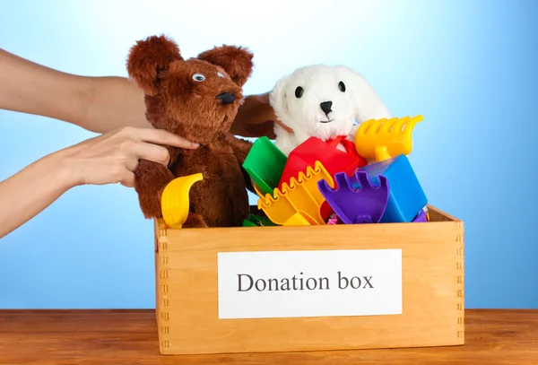 Коробка для пожертвований с детскими игрушками на синем фоне крупным планом — стоковое фото