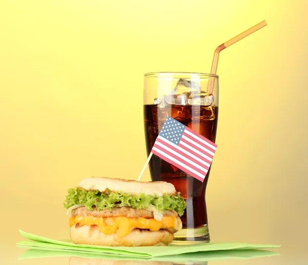 Tasty sandwich with american flag and cola, on yellow background — Stock Photo, Image