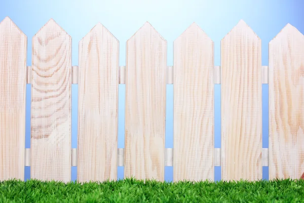 木製のフェンスと青色の背景に緑の草 — ストック写真