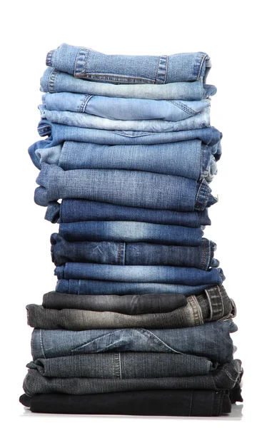 Många jeans staplade i en hög isolerad på vit — Stockfoto