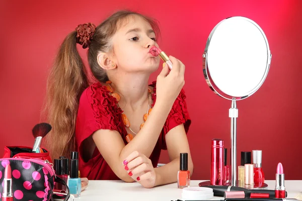 Маленькая девочка в мамином платье, пытается покрасить губы — стоковое фото