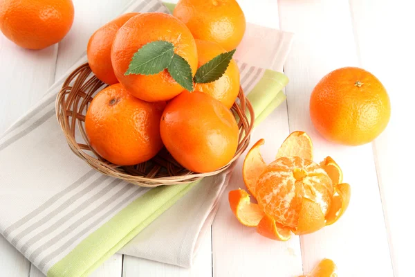 Mandarinen mit Blättern in einem schönen Korb, auf weißem Holztisch — Stockfoto