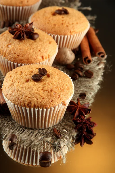 Tasty muffin cakes on burlap, spices and coffee seeds, on brown background — Zdjęcie stockowe