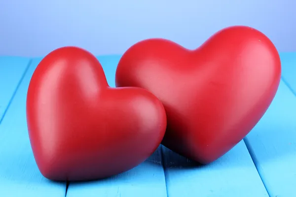 Corazones rojos decorativos sobre mesa de madera azul sobre fondo azul —  Fotos de Stock