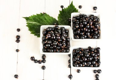 Beyaz ahşap zemin yakın çekim üzerinde ahşap kase taze Siyah frenk üzümü