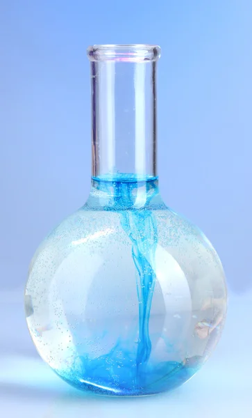 Brightly ink in a flask with water on blue background — Stock Photo, Image