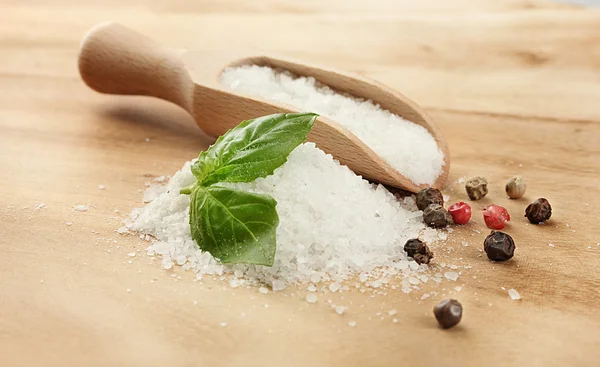 Соль со свежим базиликом, чесноком и перцем на деревянном столе — стоковое фото