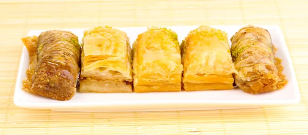 Sweet baklava on plate on bamboo mat — Zdjęcie stockowe