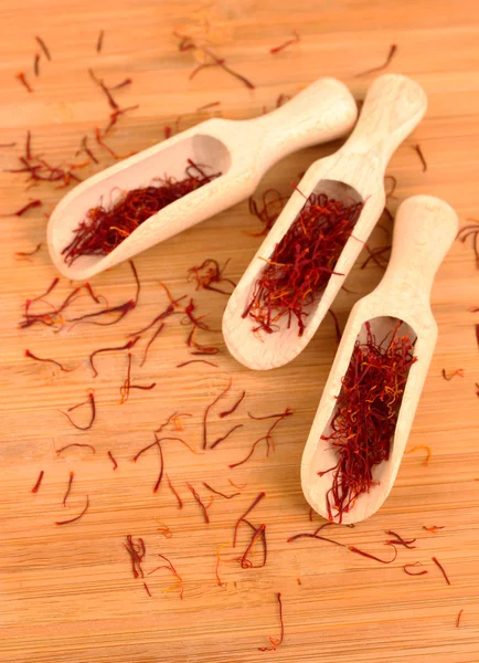 Stigmas of saffron in wooden spoons on wooden background close-up — Stock Photo, Image