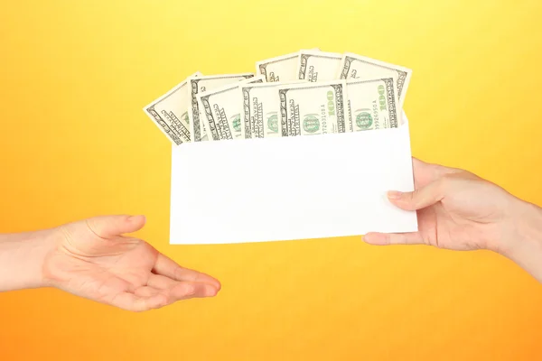 A mão da mulher passa o envelope com o salário no fundo amarelo — Fotografia de Stock
