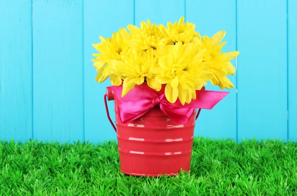 Mooi boeket van chrysanten in een heldere kleurrijke emmer op blauwe fen — Stockfoto