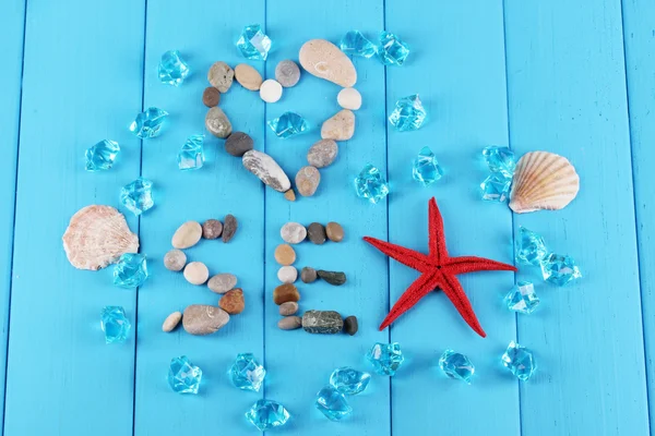 A palavra mar e decoração de conchas close-up na mesa de madeira azul — Fotografia de Stock