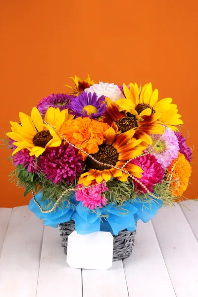 Schöner Strauß heller Blumen mit Papiernote auf Holztisch auf oran — Stockfoto