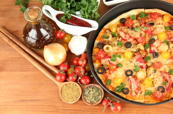 Kleurrijke samenstelling van heerlijke pizza, groenten en specerijen op houten ba — Stockfoto