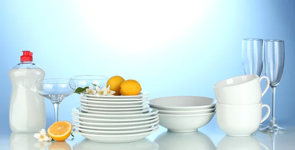 Empty clean plates, glasses and cups with dishwashing liquid and lemon on b — Stock Photo, Image