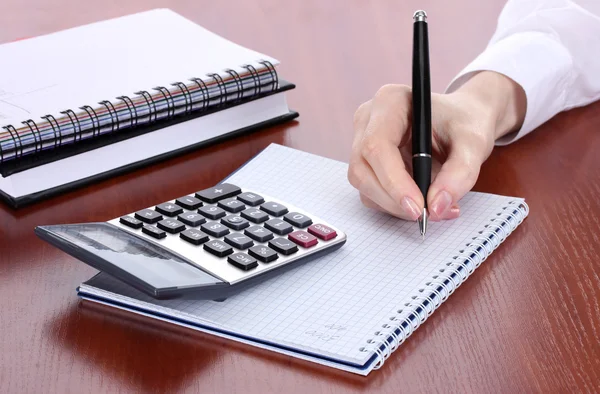Ręce kobiety z ołówkiem, notebooki i kalkulator na drewnianym stole — Zdjęcie stockowe