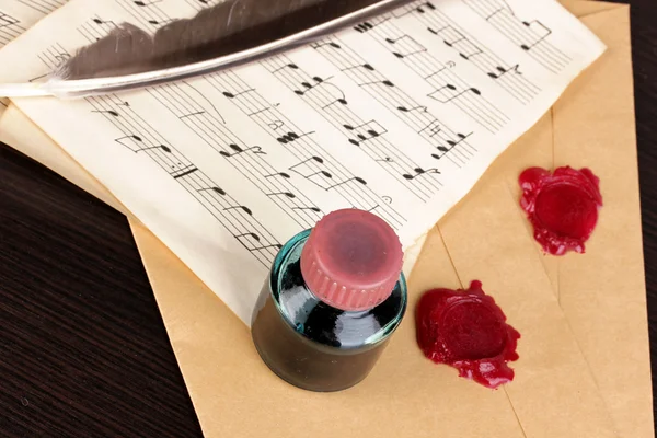 Musical notes and feather on wooden table — Stock Photo, Image