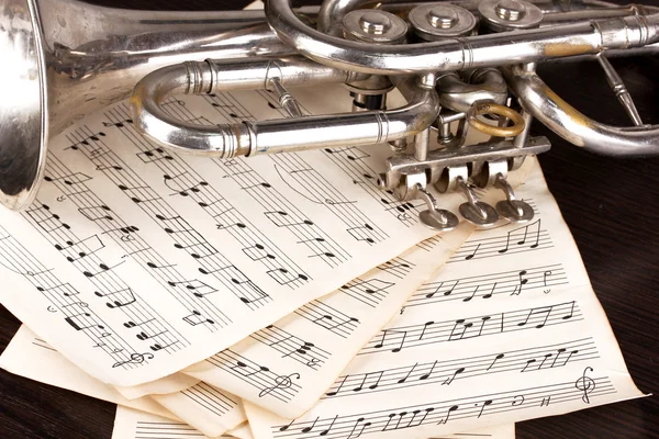 Notas musicais e trompete na mesa de madeira — Fotografia de Stock