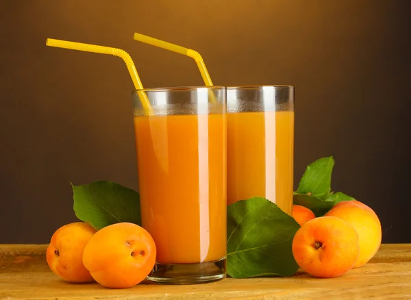 Glasögon av aprikos juice på träbord på brun bakgrund — Stockfoto