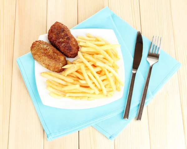 Potatis pommes frites med hamburgare på plattan på trä bakgrund närbild — Stockfoto