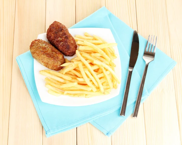 Batatas fritas com hambúrgueres no prato em fundo de madeira close-up — Fotografia de Stock