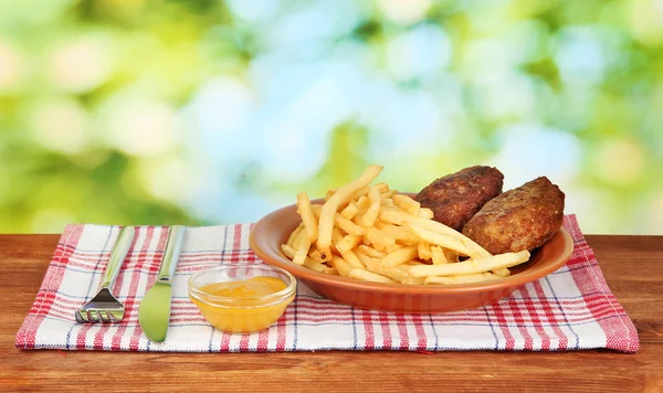 Patatas fritas con hamburguesas en el plato sobre fondo verde de cerca —  Fotos de Stock