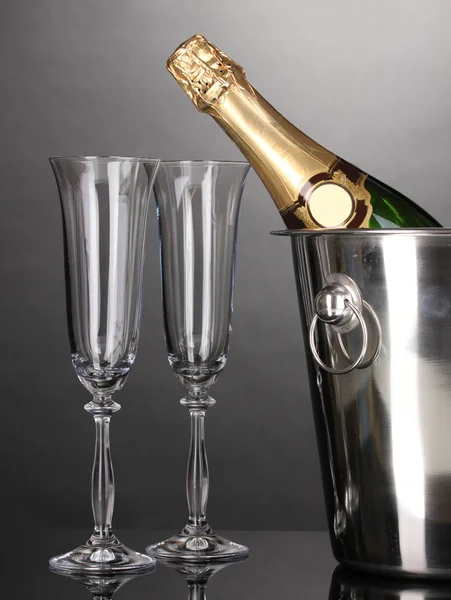 Champagne bottle in bucket with ice and glasses on grey background — Stock Photo, Image