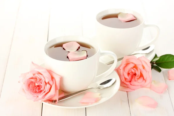 Tazze di tè con rose sul tavolo di legno bianco — Foto Stock