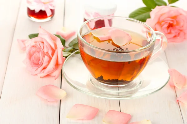 Taza de té con rosas y mermelada en mesa de madera blanca — Foto de Stock