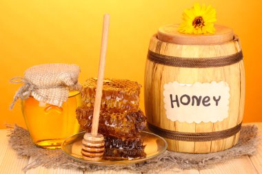 Bal ve petek turuncu zemin üzerine ahşap masa üzerinde varil