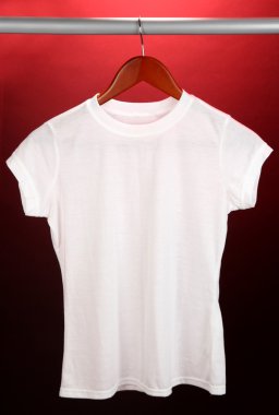 Askı üzerinde kırmızı zemin üzerinde beyaz t-shirt
