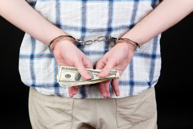 adam kelepçeli siyah arka plan üzerine dolar tutuyor