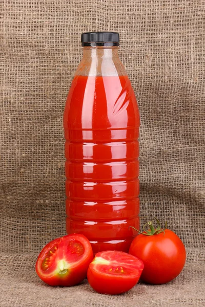 Sumo de tomate em garrafa sobre fundo de pano de saco — Fotografia de Stock