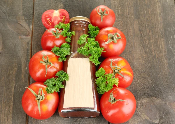 Ketchup em garrafa e tomates em mesa de madeira — Fotografia de Stock