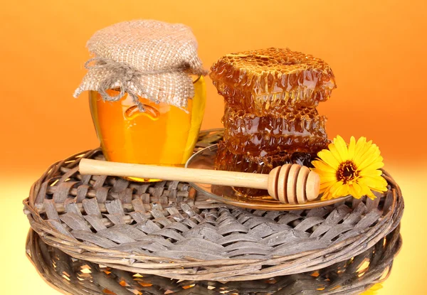 Sklenice medu a plástve na oranžovém pozadí — Stock fotografie