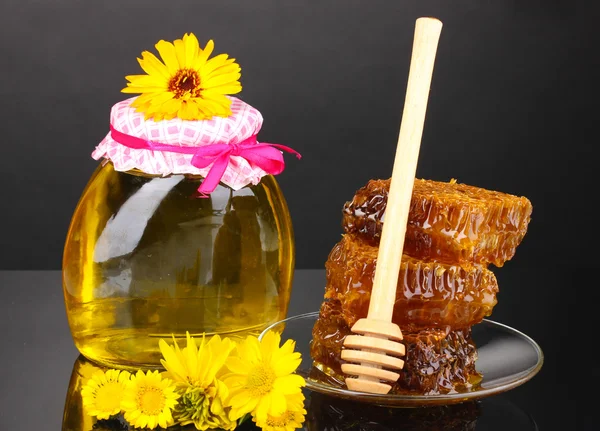 Vaso di miele e favo su fondo nero — Foto Stock