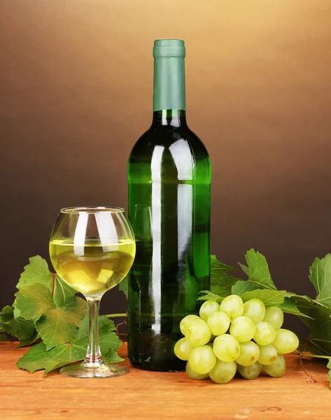 Flasche großer Wein mit Glas auf Holztisch auf braunem Hintergrund — Stockfoto