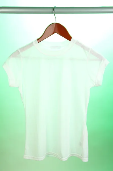 White t-shirt on hanger on green background — Stock Photo, Image