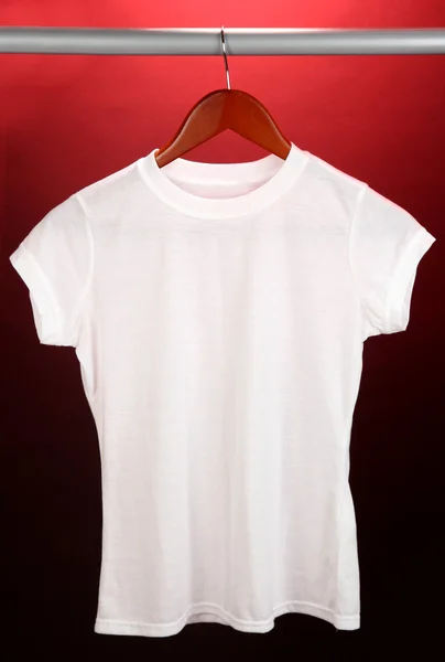 Camiseta blanca en percha sobre fondo rojo — Foto de Stock