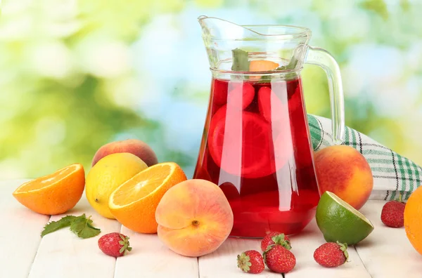 Sangria in jar with fruits, on wooden table, on green background — Stock Photo, Image