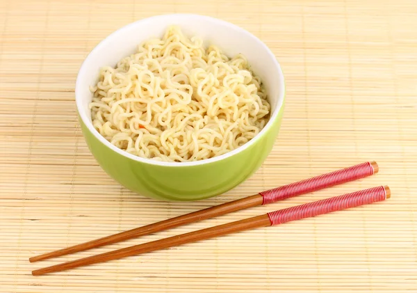 Asian noodles in bowl on bamboo mat — Stock Photo, Image