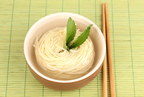 Tagliatelle asiatiche in ciotola su tappetino di bambù — Foto Stock