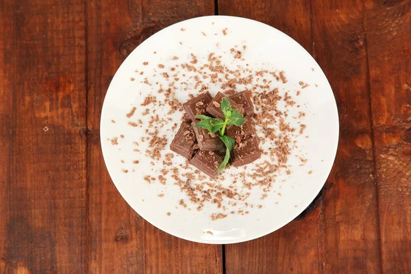 Briciola di cioccolato con menta sul piatto su uno sfondo di legno primo piano — Foto Stock