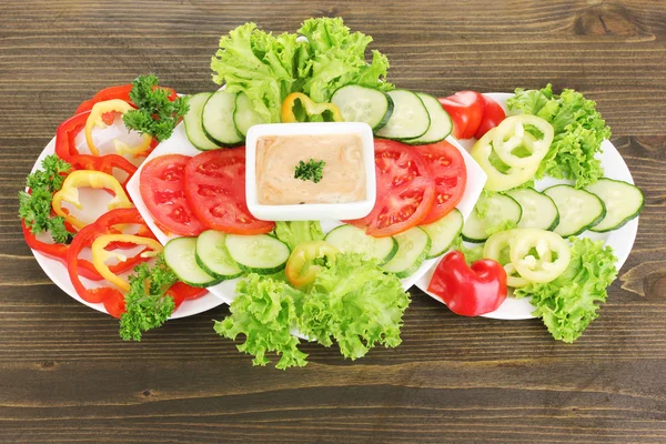 Gehakte groenten en saus op plaat op houten tafel — Stockfoto