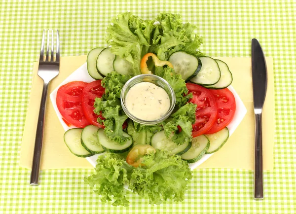 Ψιλοκομμένο λαχανικά και σάλτσα στο πιάτο στο πράσινο τραπεζομάντιλο — Φωτογραφία Αρχείου