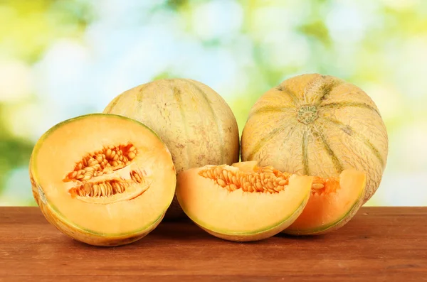 Cut melon on wooden table on green background — Stock Photo, Image